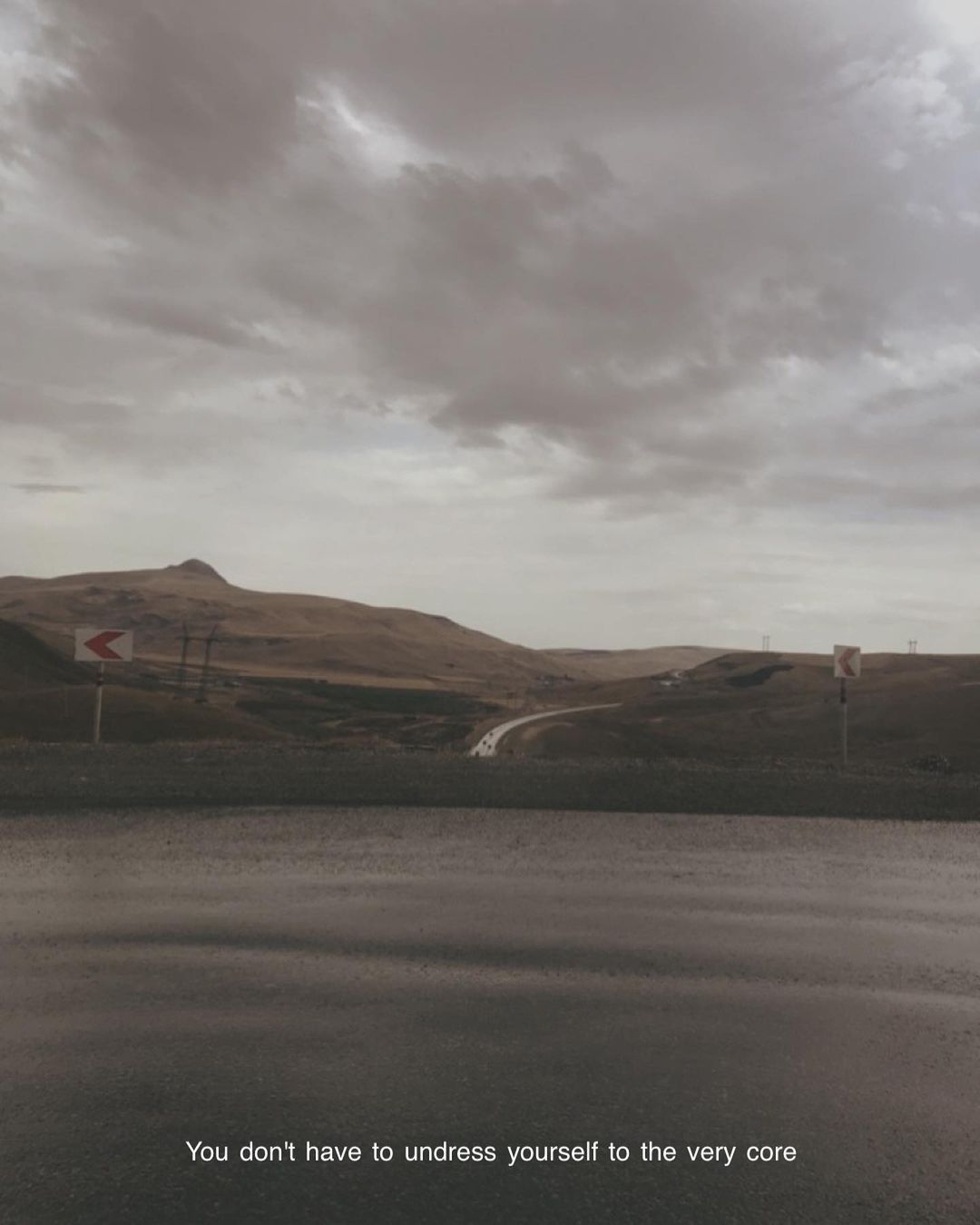 A winding road through brown hills beneath a heavy grey sky
